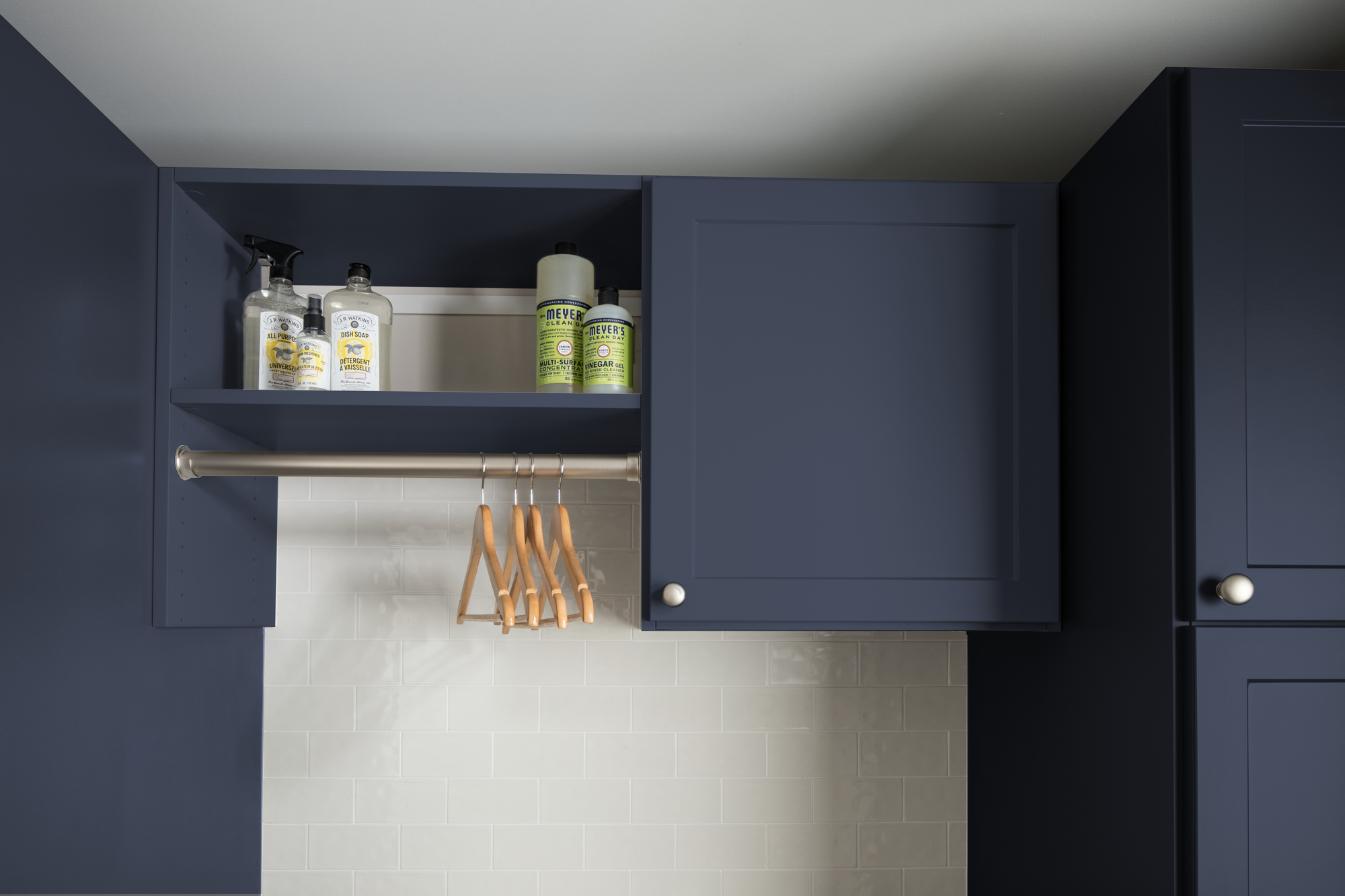 Hanging storage and cupboard storage for navy blue laundry room