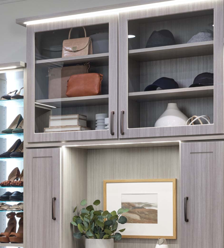 A wardrobe in a walk in closet with purses and hats.