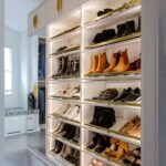 Slanted white shoe shelves with matte brass accents in an Inspired Closets boutique closet.