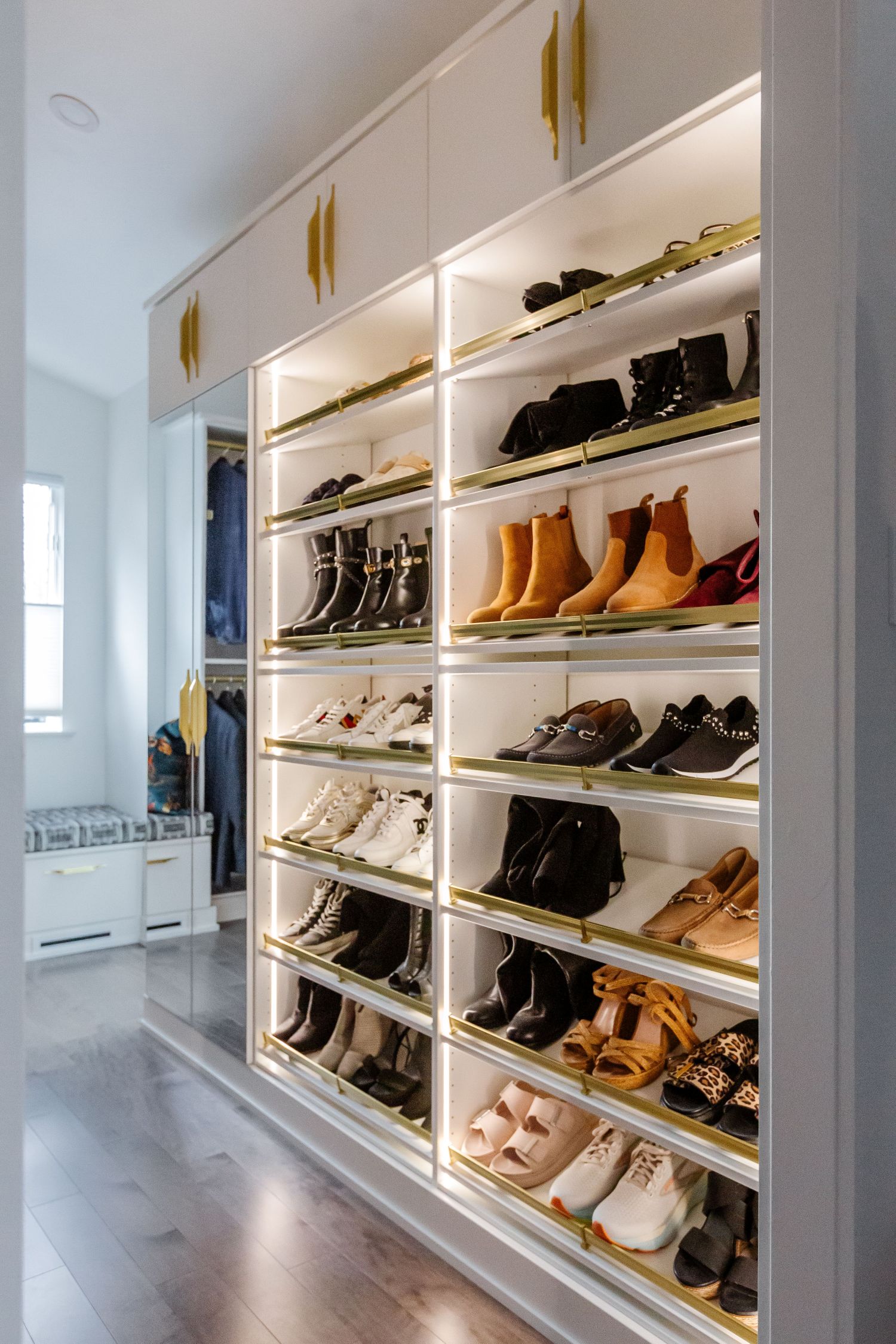 Slanted white shoe shelves with matte brass accents in an Inspired Closets boutique closet.
