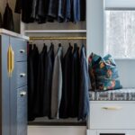 Ore, white, and matte brass hardware in a custom boutique Inspired Closets walk-in closet.