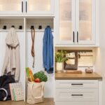 Entryway 3 Custom entryway with glass-front cabinets above and a mix of hook storage, open shelves, and soft-close drawers below to hold coats, easy drop zone items, and accessories, in a warm white finish, medium wood tone tops, and matte black hardware