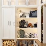 Entryway 4 Custom entryway with glass-front cabinets above and locker-style cabinets below for sports equipment, firewood, and miscellaneous storage in a warm white finish with matte black hardware