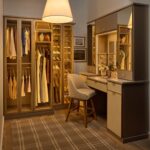 Her custom closet with glass-front cabinets for clothes and shoe organization, and a vanity with soft-close drawers, integrated lighting, mirrored door fronts, leather drawer fronts, and matte brass and gold accents