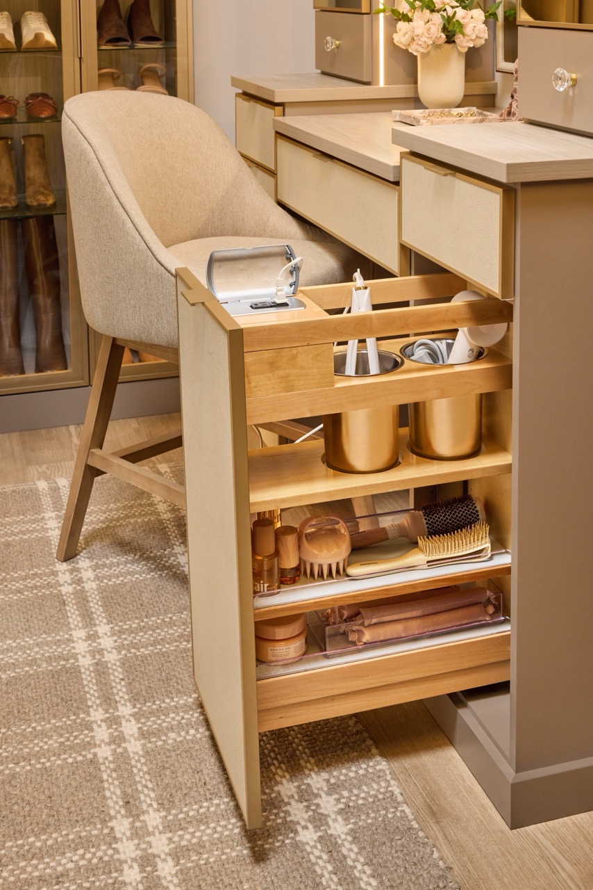 Close up of a custom vanity with a powered, pull-out drawer for beauty storage, leather drawer fronts, and matte brass and gold accents