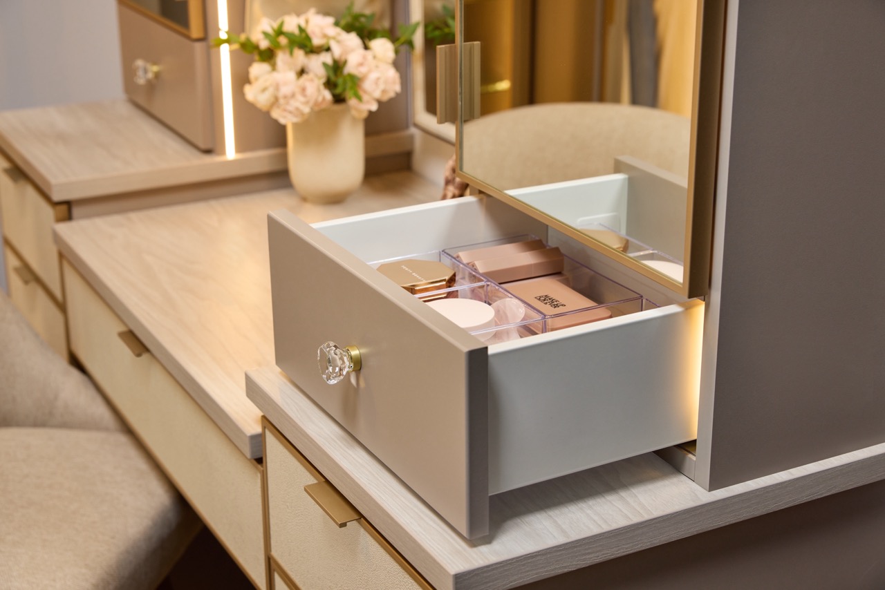 Close up of a custom vanity with soft-close drawers, mirrored door fronts, integrated lighting, leather drawer fronts, and matte brass and gold accents