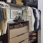 His reach-in closet featuring soft-close drawers with Seared brown fronts, hanging clothes rods, open shelf storage holding shoes, duffle bag, folded clothes, and personal items, in a mix of medium wood and onyx tones, Elusion glass top, and matte black hardware