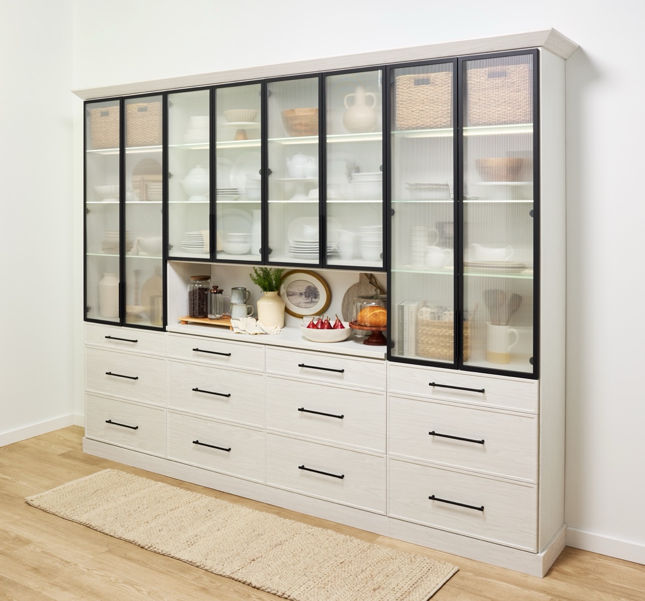 Custom hutch in a light wood-tone finish with matte black hardware, black-framed doors with reeded-glass fronts, and a prep counter in the center