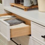 Detail of a custom hutch soft-close drawer in a light wood-tone finish with black hardware, opened to show linens inside