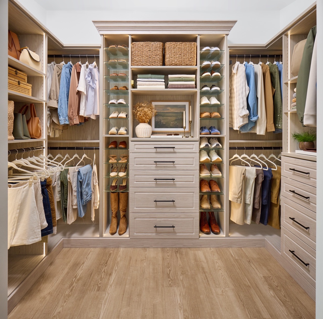 Shared walk-in closet for a man and woman in a light wood-tone finish with custom storage, Shoe Shrine, valet rod, and belt rack